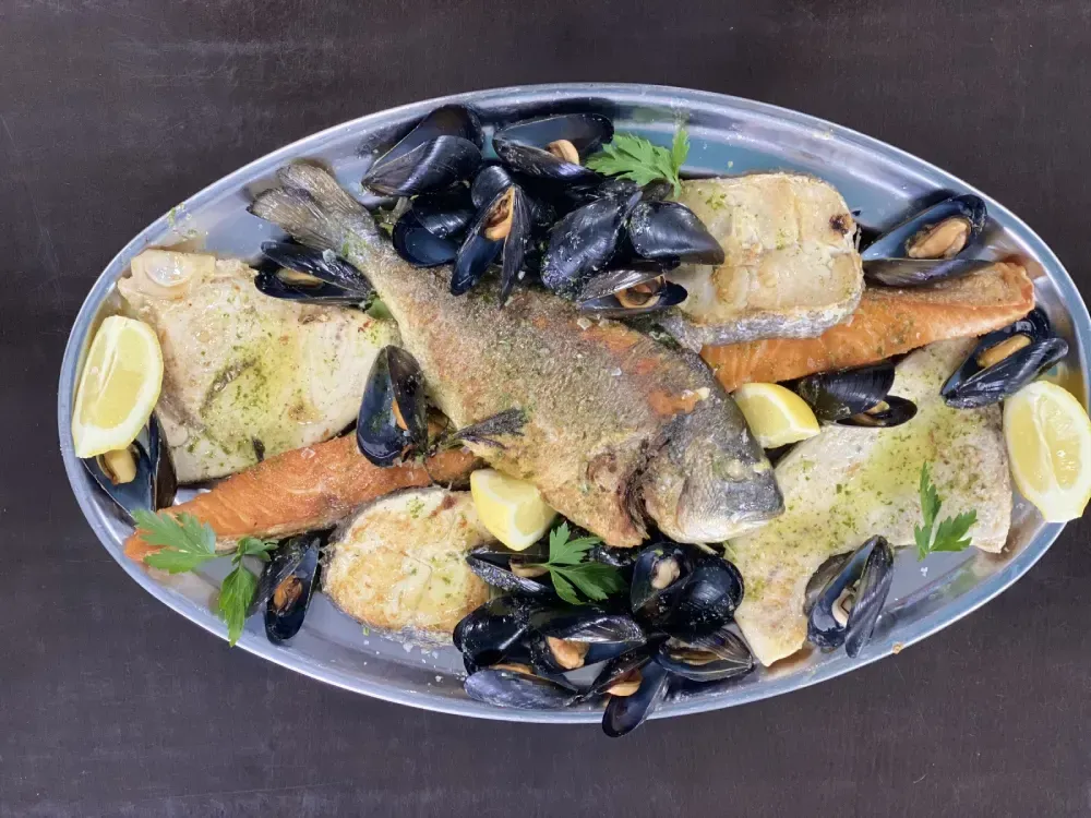 Bistec con patatas fritas, sal y salsa en un plato negro.