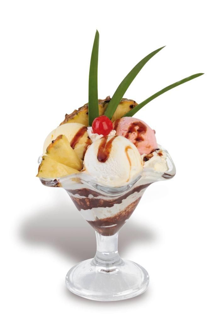 Sundae de helado en copa, con piña, cereza, salsa de chocolate y ramitas verdes.