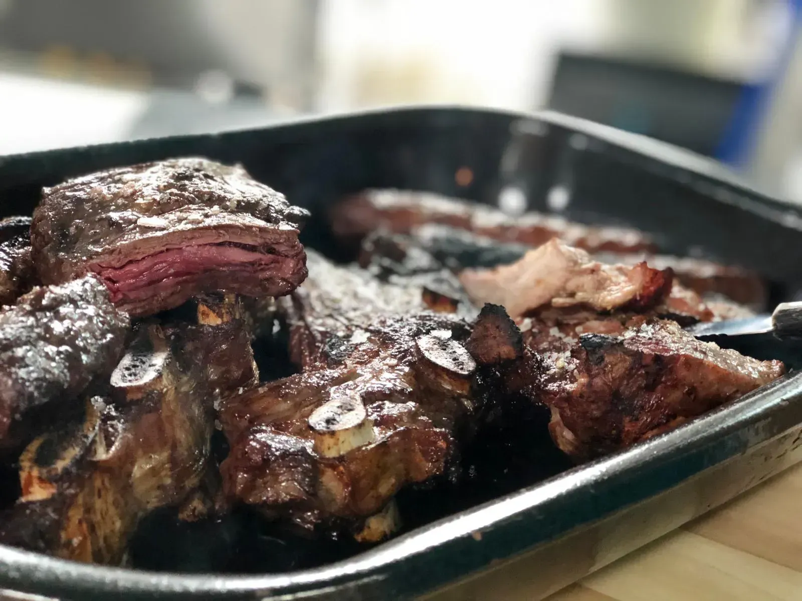 Bistec con patatas fritas, sal y salsa en un plato negro.