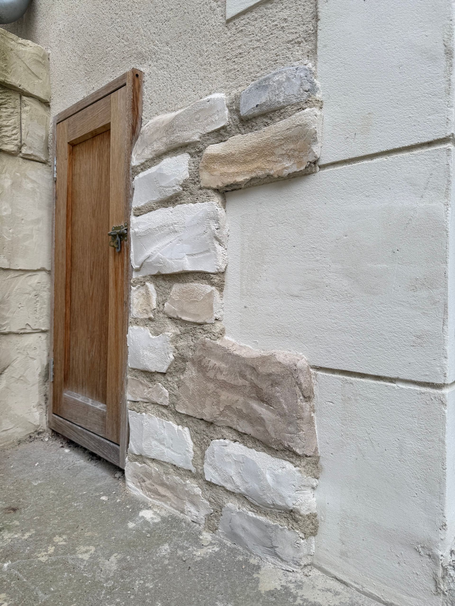 Mur en pierre et en stuc avec porte en bois, illustrant les différences de construction.