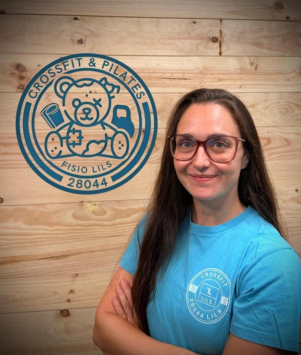 Mujer con gafas y los brazos cruzados, se encuentra frente a un logotipo que dice 