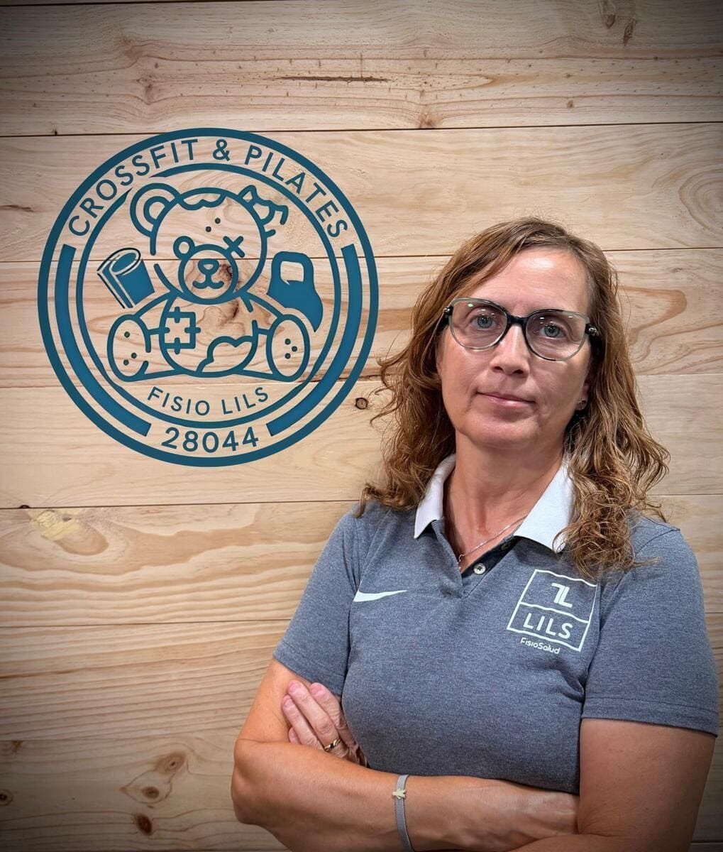 Mujer con gafas y los brazos cruzados, se encuentra frente a un logotipo que dice 