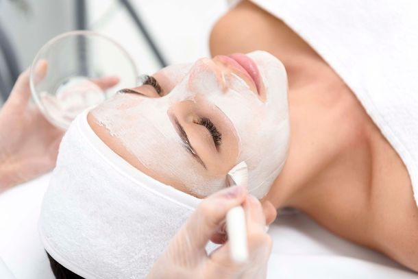 Eine Frau bekommt eine weiße Maske aufs Gesicht
