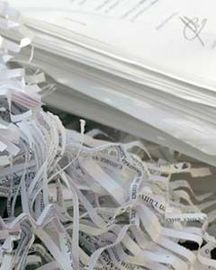 Pile de feuilles de papier blanches déchiquetées, mêlées à des bandes de papier issues d’un destructeur de documents.