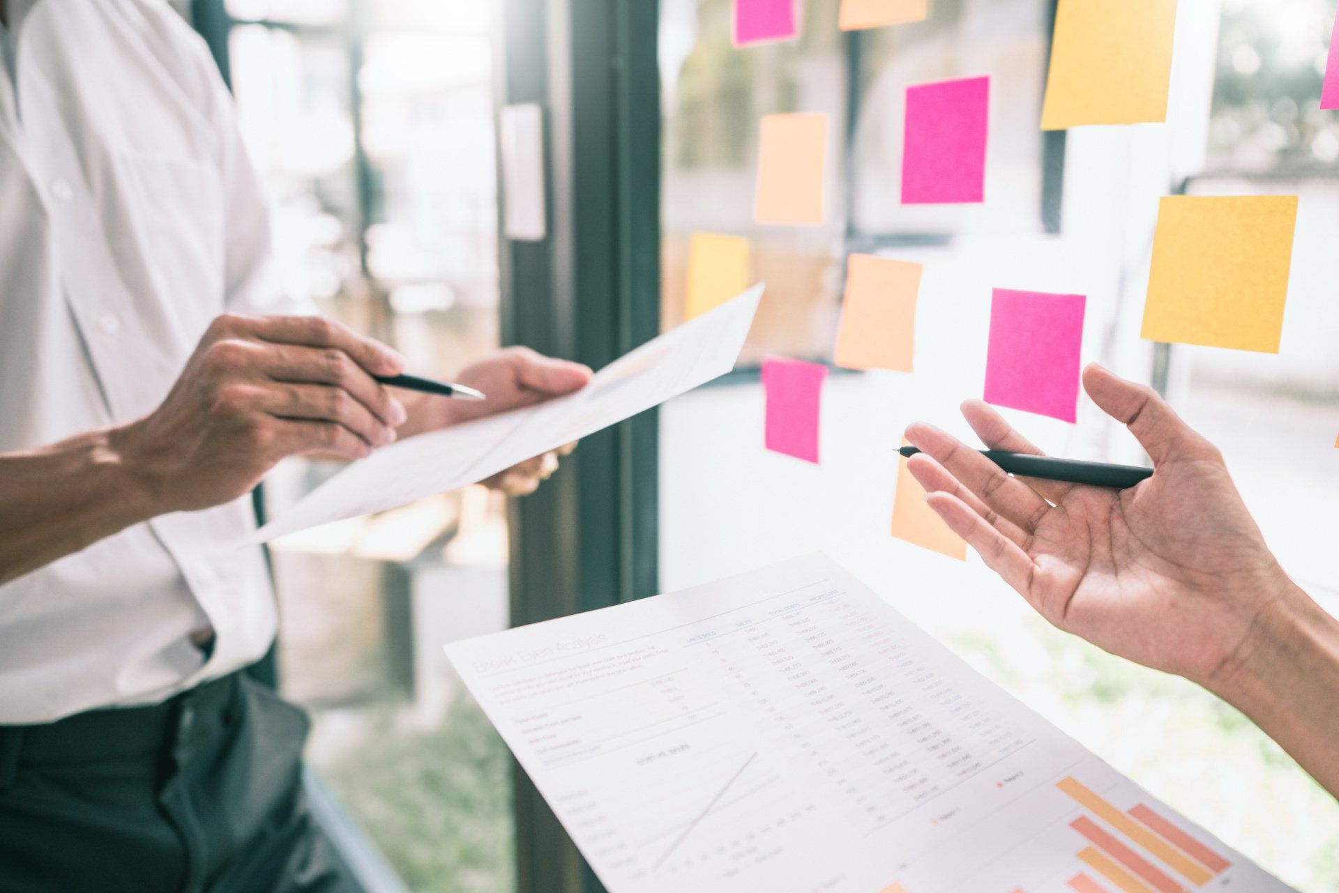 Deux personnes étudiant les comptes devant un vitre remplie de post-it