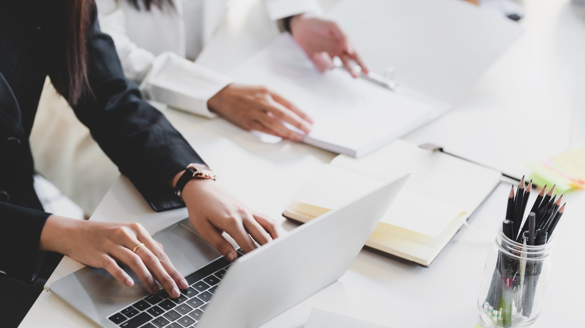 Une personne prenant des notes, l'autre consultant des documents