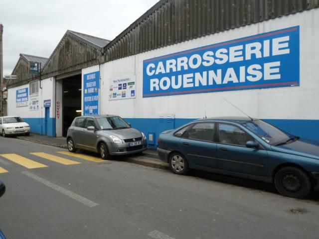 La façade de la Carrosserie Rouennaise, un garage automobile avec des voitures garées devant.