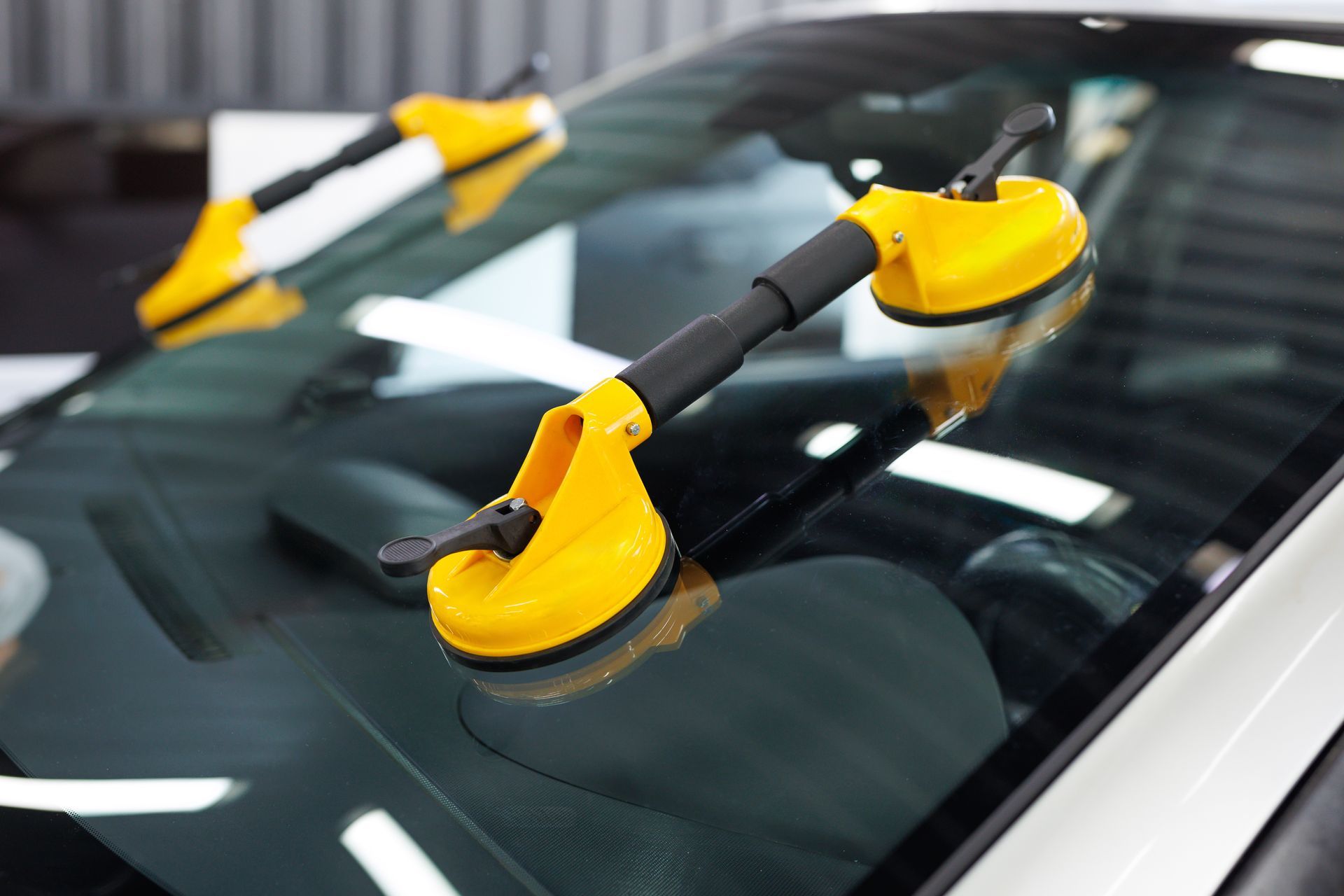 Deux poignées à ventouses jaunes fixées au pare-brise d'une voiture.