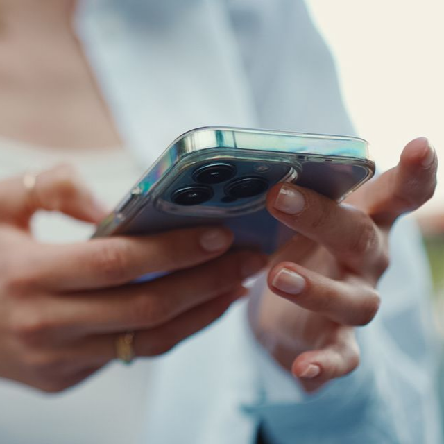 Gros plan sur des mains tenant un smartphone à triple objectif, interagissant avec l'écran.