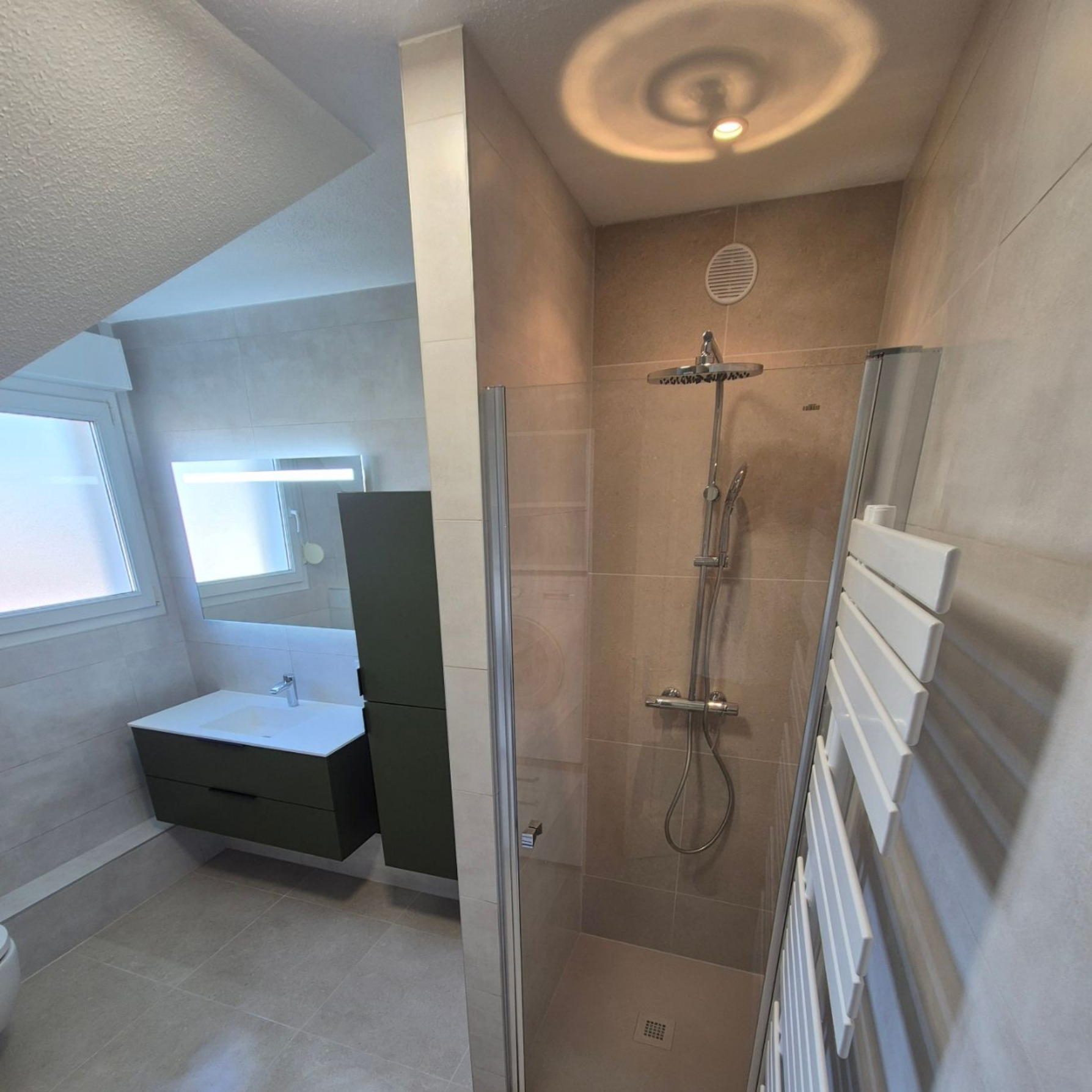 Salle de bains moderne avec douche, meuble-lavabo et sèche-serviettes.