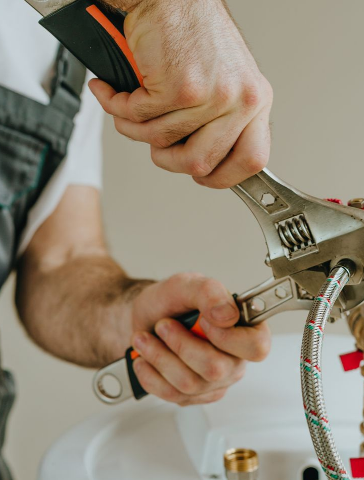 Un plombier utilise une clé pour serrer un raccord sur un chauffe-eau.