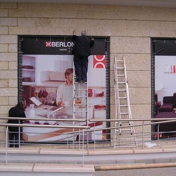 Un hombre parado en una escalera frente a un cartel que dice Berlon.