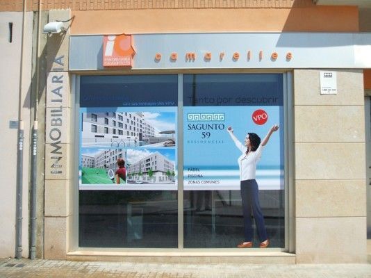 Una mujer está parada frente a una ventana que dice inmobiliaria