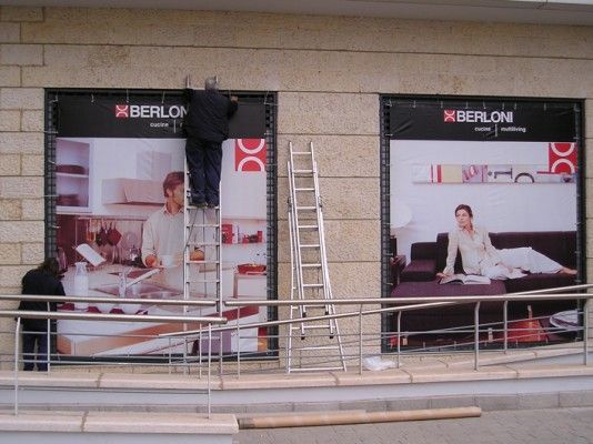 Un hombre en una escalera está trabajando en un cartel para Xberlon.