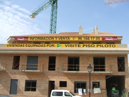 Una camioneta blanca está estacionada frente a un edificio que dice visite piso piloto