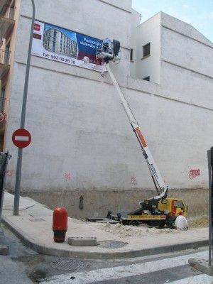 Una grúa está en el costado de un edificio al lado de una señal de prohibición de entrada.