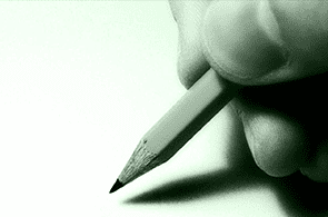 Una persona está escribiendo con un lápiz en un trozo de papel.
