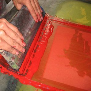 Una persona está esparciendo pintura roja sobre una pantalla.