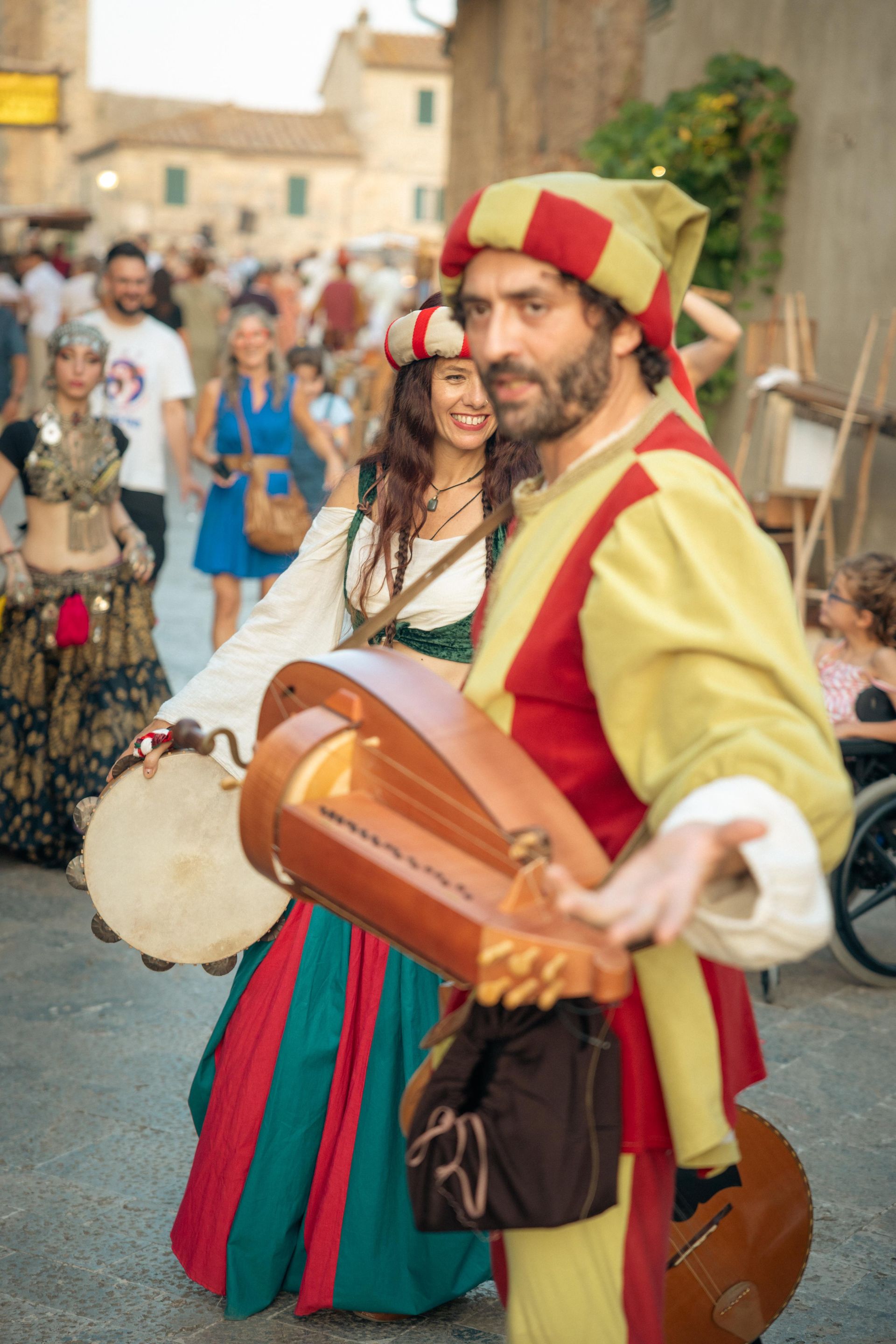 Artistas callejeros medievales disfrazados: hombre con instrumento de cuerda, mujer con pandereta