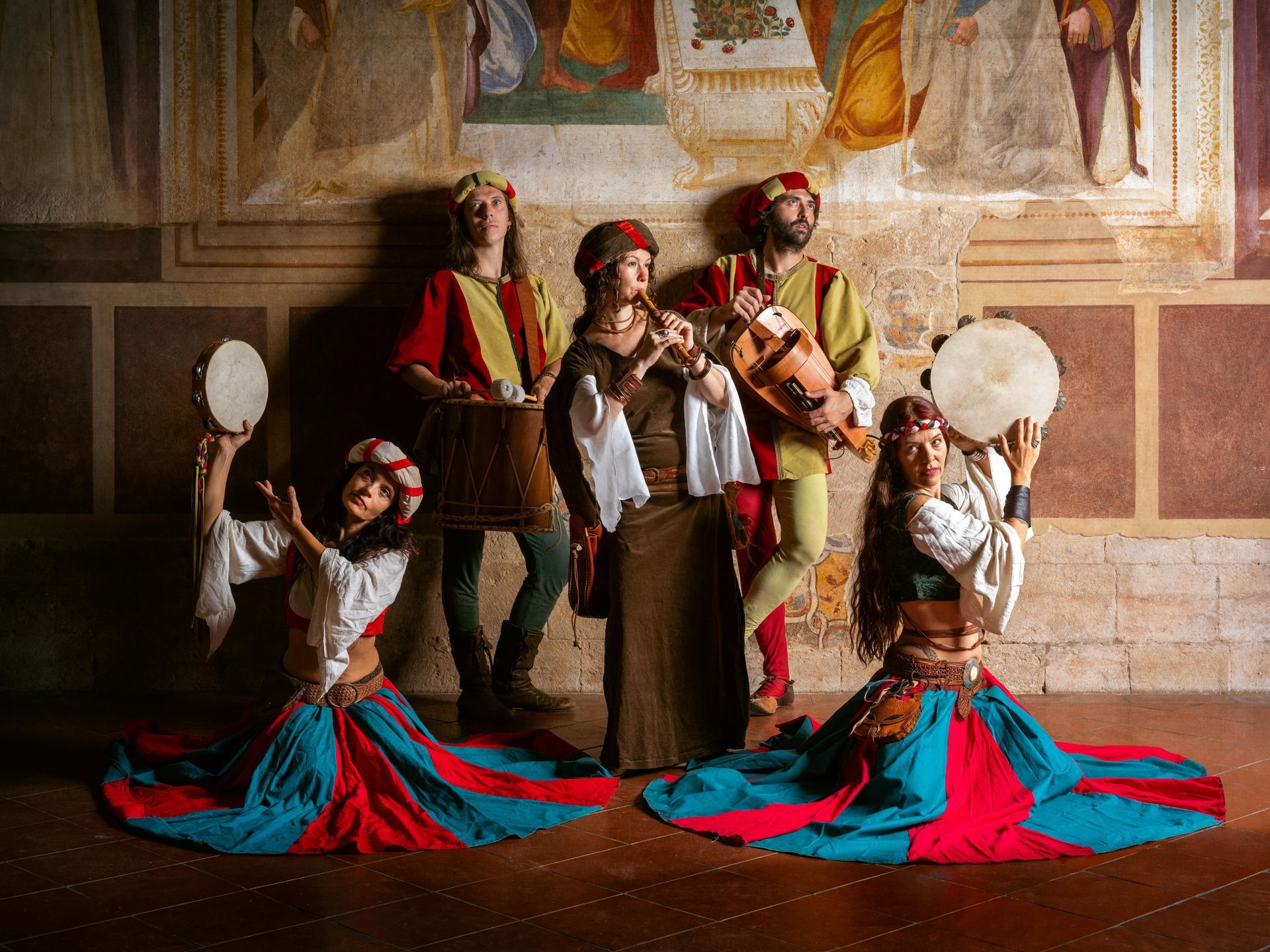 Un conjunto musical disfrazado con flauta, laúd y panderetas en una sala con frescos.