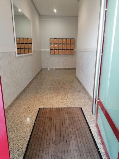 Un pasillo con un espejo y buzones en la pared.