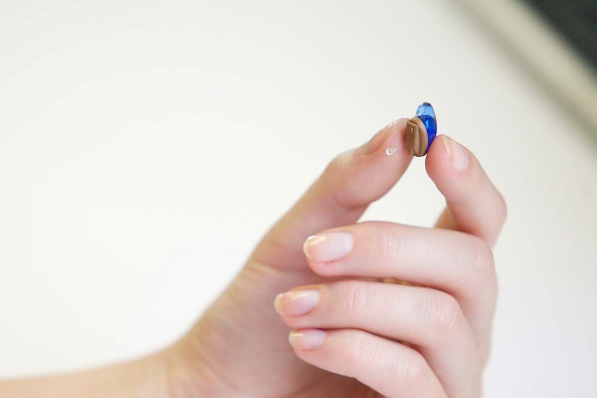 Main de femme tenant un appareil intra-auriculaire