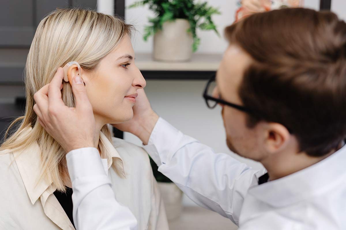 Professionnel installe un appareil auditif sur une femme