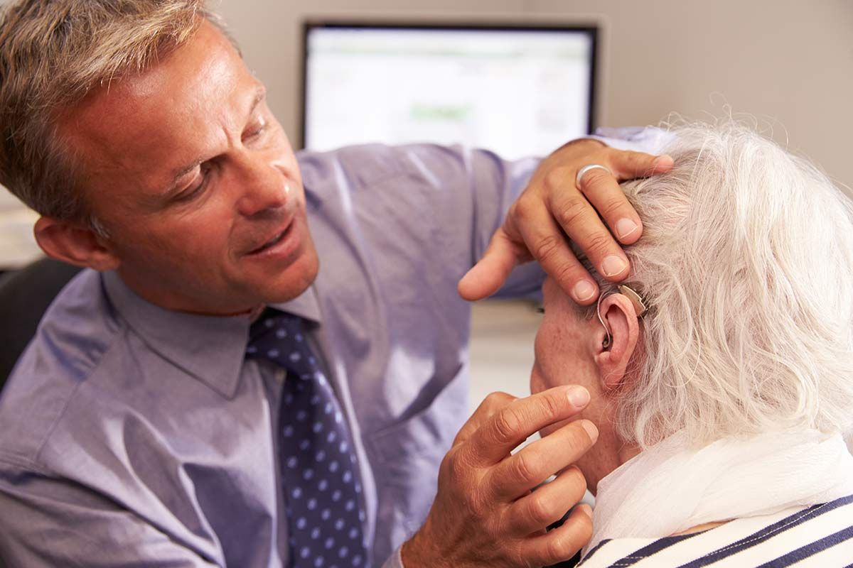 Homme règle l'appareil auditif d'une personne âgée