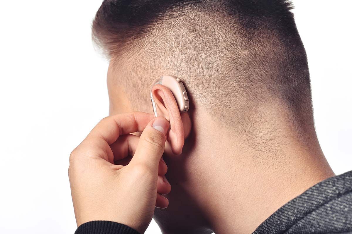 Homme qui place son appareil auditif à son oreille