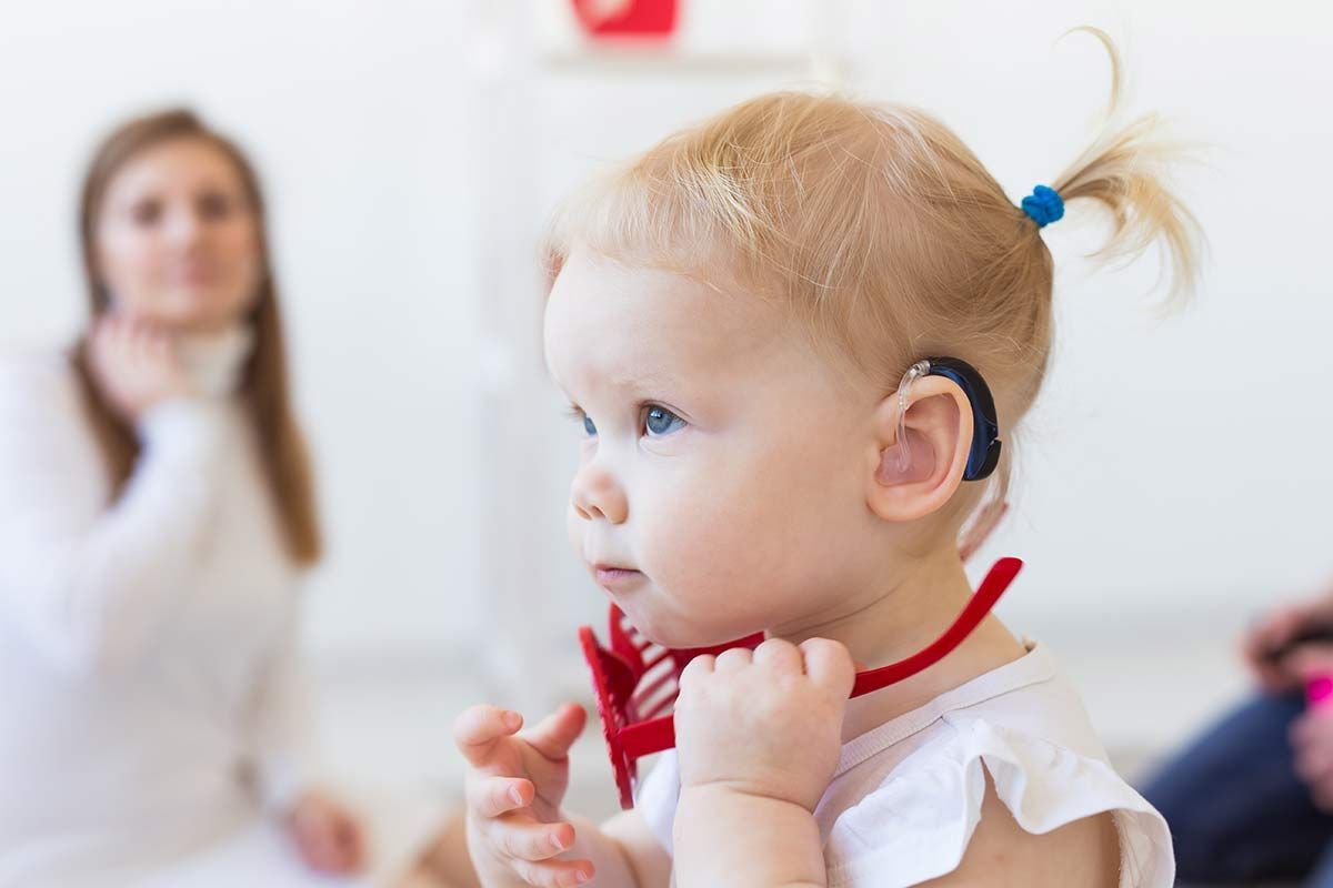 Jeune enfant blond portant un appareil auditif