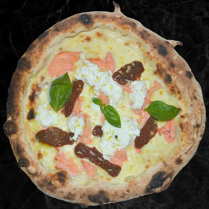 Una pizza con muchos ingredientes encima está sobre una mesa.