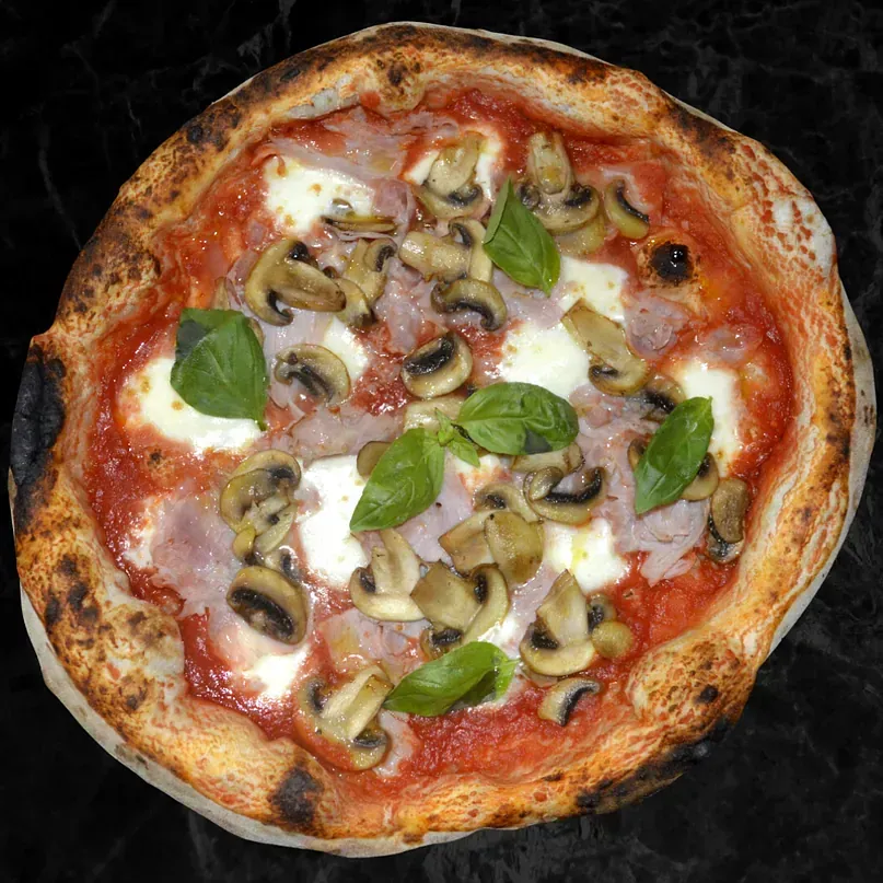 Una pizza con champiñones y albahaca encima.