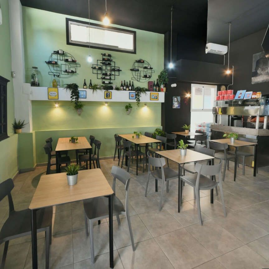 Mesas y sillas en un restaurante con una pared verde.