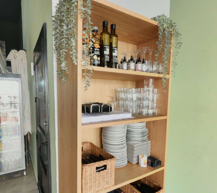 Un estante de madera con botellas y vasos encima.