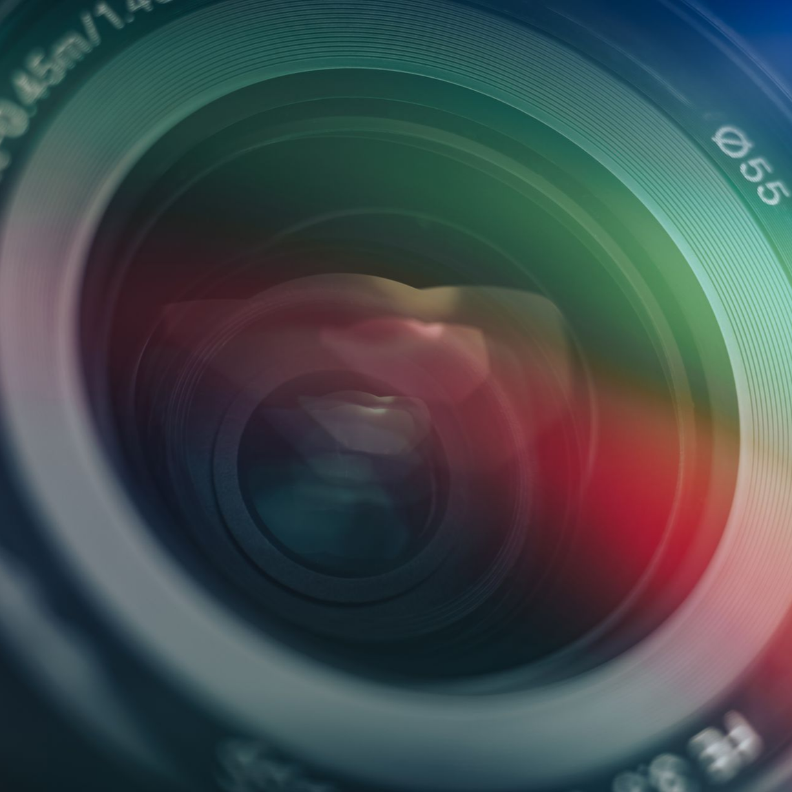 Vue rapprochée d'un objectif d'appareil photo, avec un reflet lumineux coloré et des éléments rouges, verts et bleus.