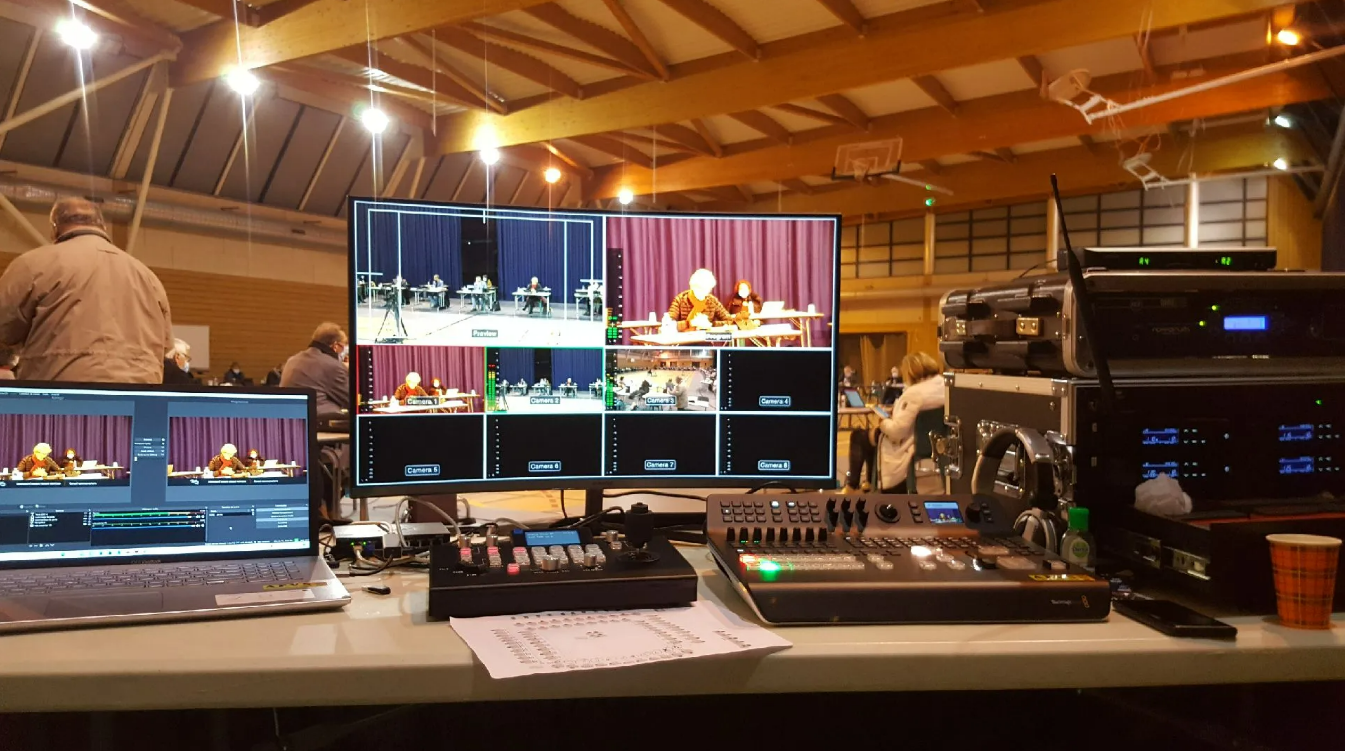 Une installation de production vidéo : plusieurs écrans diffusant des flux en direct depuis une scène, avec un tableau de contrôle et du matériel.