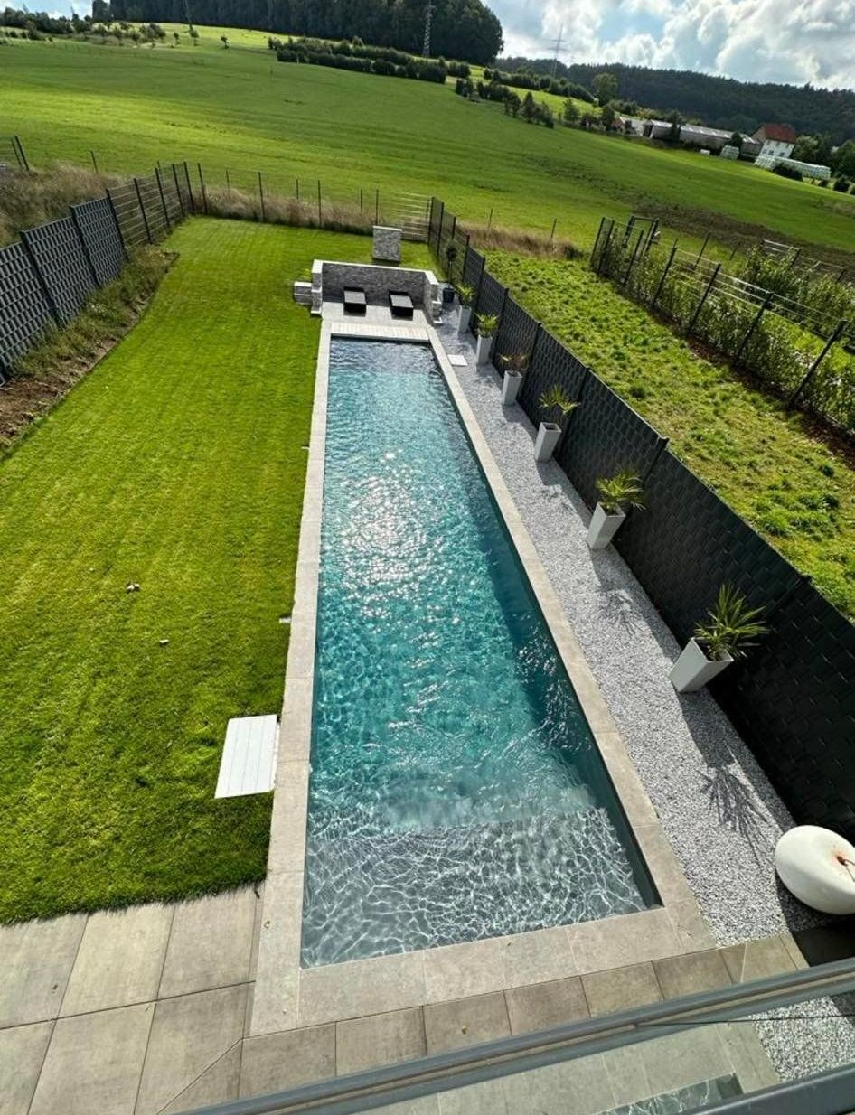 Grande piscine avec de l'herbe à côté