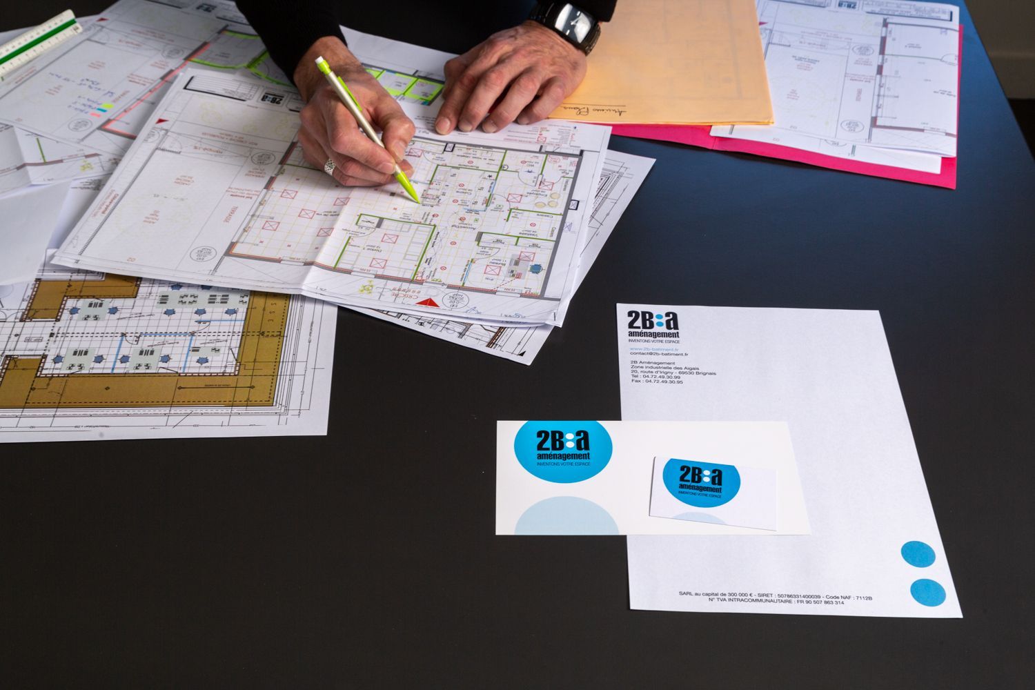 Plans d'architectes sur un bureau avec un homme dessinant dessus