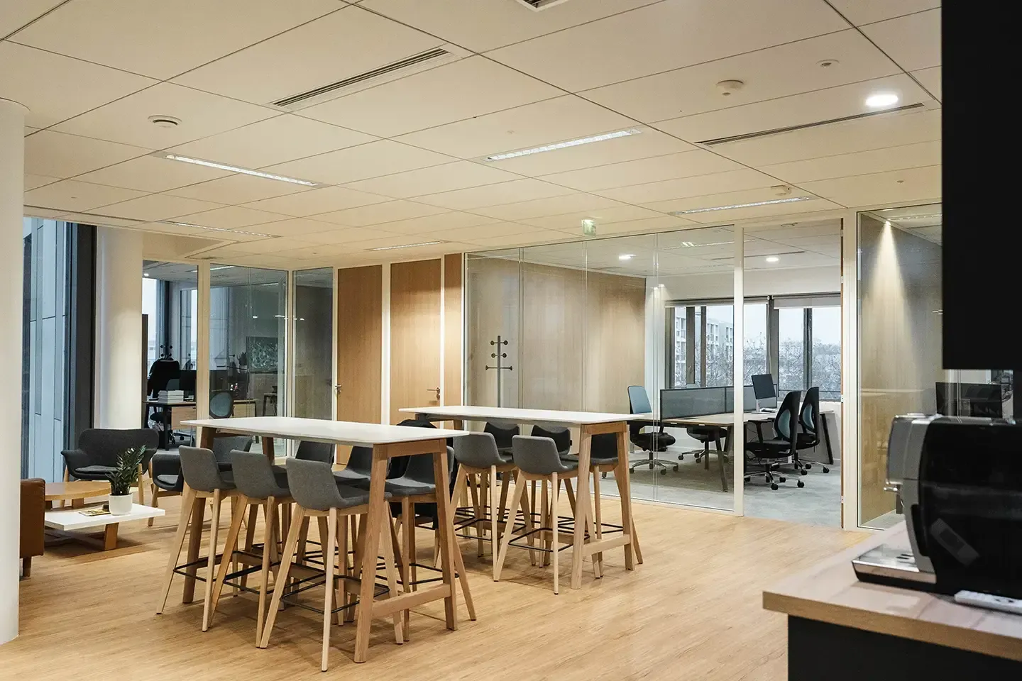 Salle de réunion avec une grande table centrale et des chaises hautes avec bureaux attenants