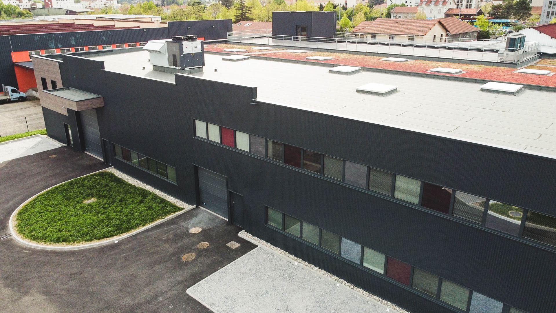 Vue en plongée de la façade d'une usine noire avec toit clair