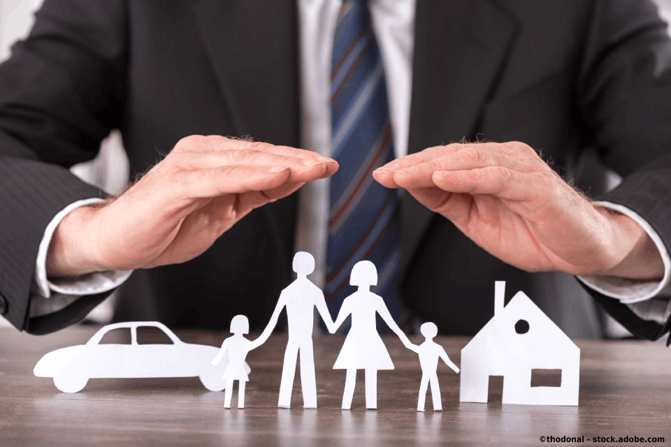 Familie aus Papier und schützende Hände des Versicherungsmakler