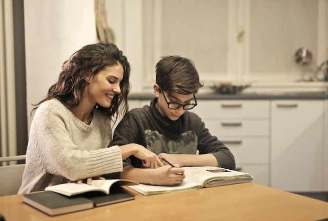 Una mujer está ayudando a un niño con su tarea en una mesa.