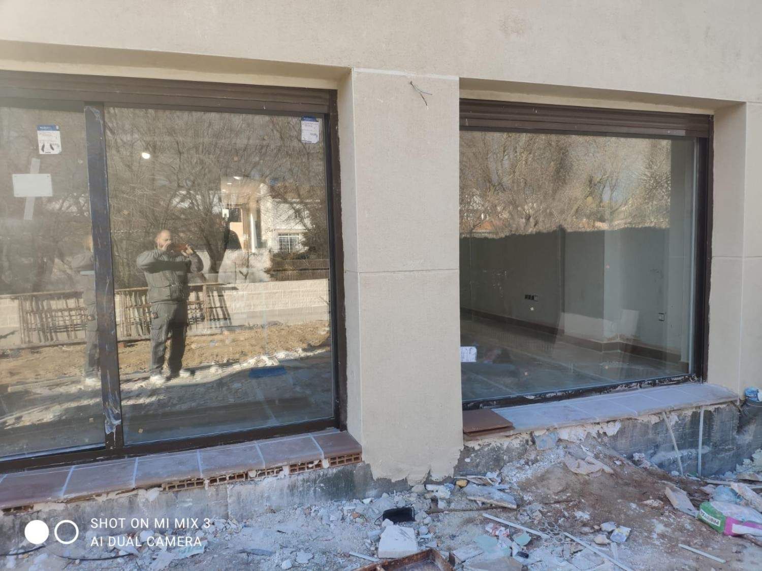 Escaparates dañados con cristales rotos y escombros esparcidos por el suelo frente a un edificio.