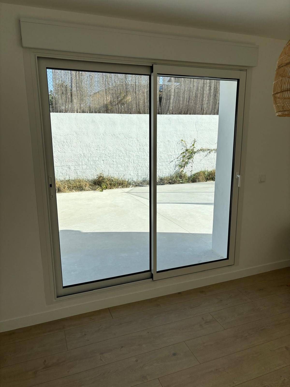 Puerta corrediza de cristal con marco beige que deja ver un patio trasero nevado y árboles en el exterior.