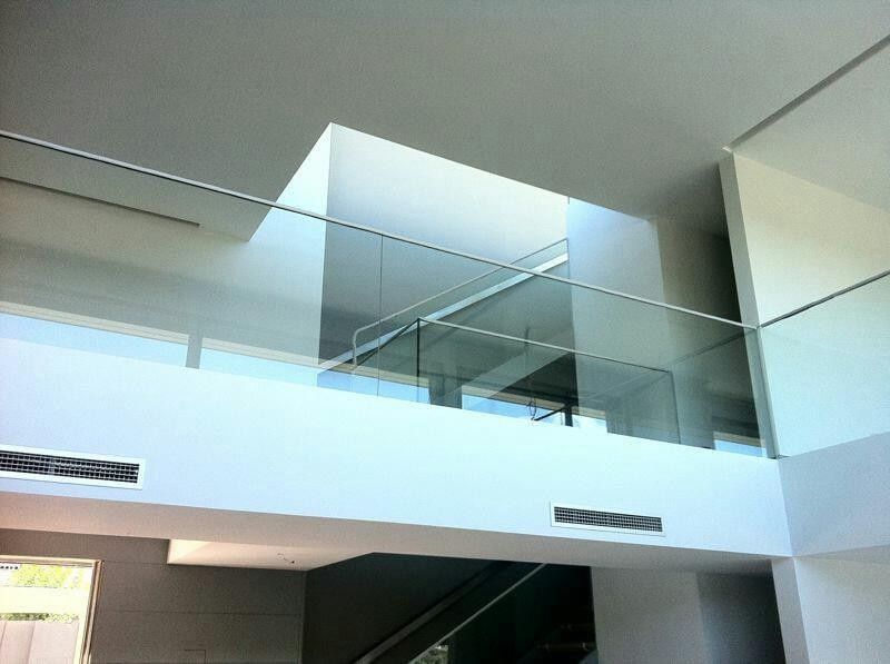 Entreplanta moderna acristalada con paredes y techo blancos en un interior luminoso.