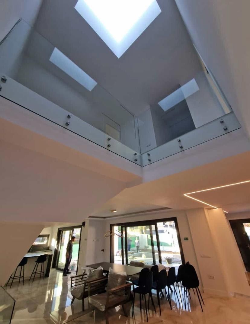 Sala de estar moderna con techo alto, tragaluces y un comedor en la planta baja.