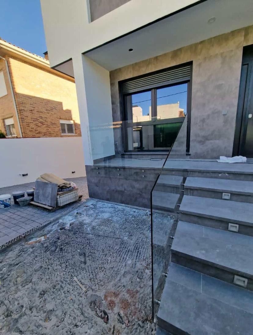 Exterior de casa moderna con escalones delanteros, fachada de piedra y un patio parcialmente terminado.