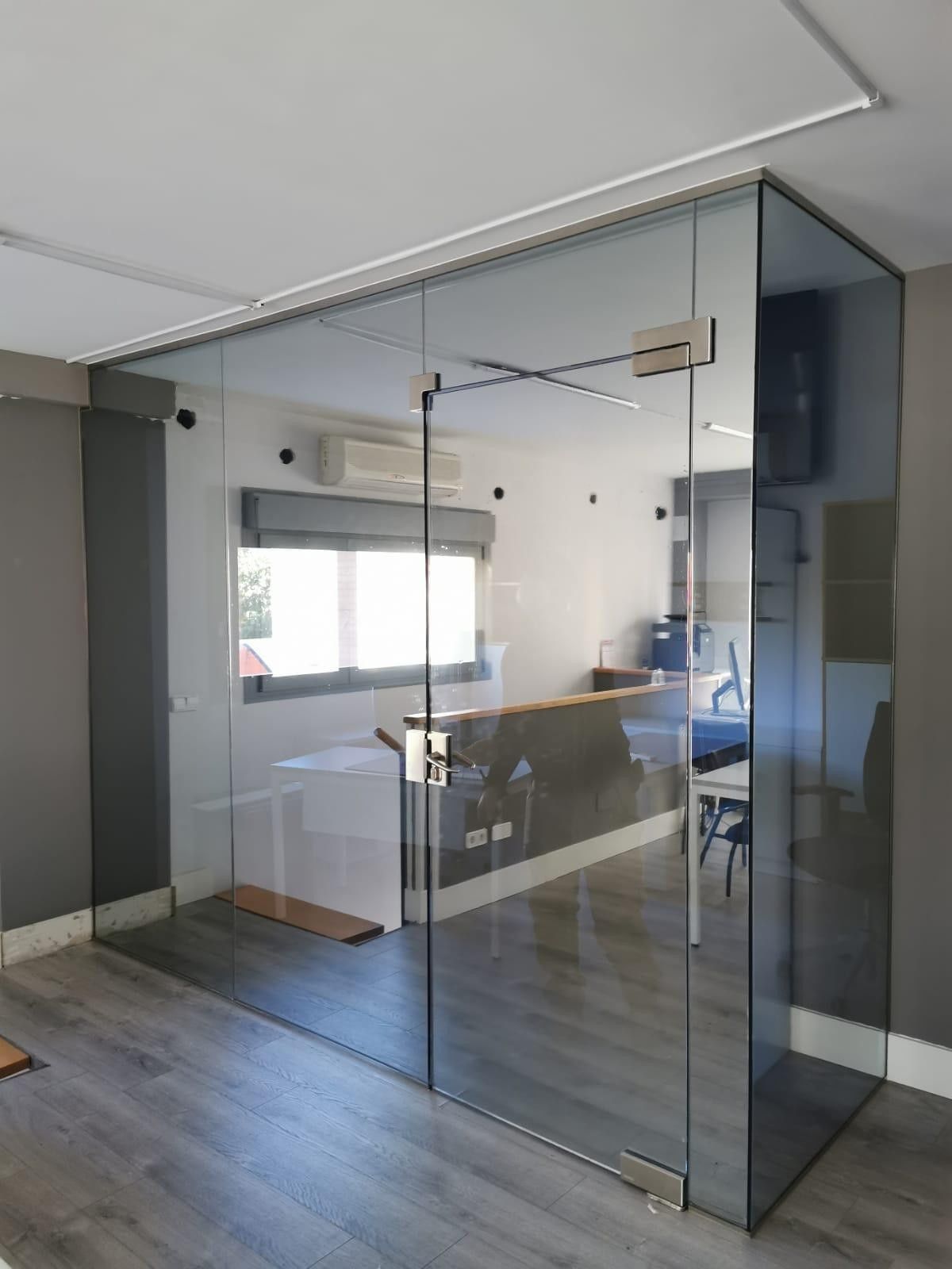 Oficina moderna con sala de reuniones con paredes de cristal y suelo de madera.