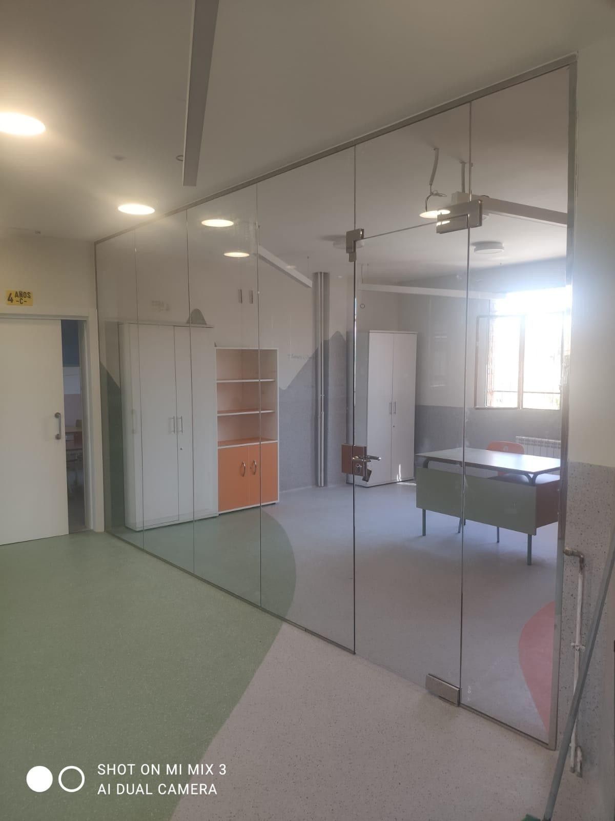 Habitación vacía con paredes divisorias de cristal, ventiladores de techo, armarios y una mesa de billar