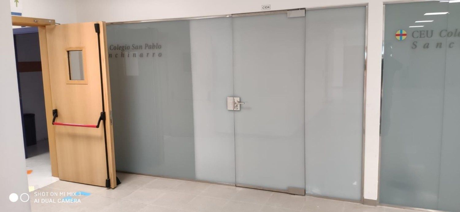 Pasillo interior con puertas de cristal tipo oficina y una puerta de madera a la izquierda